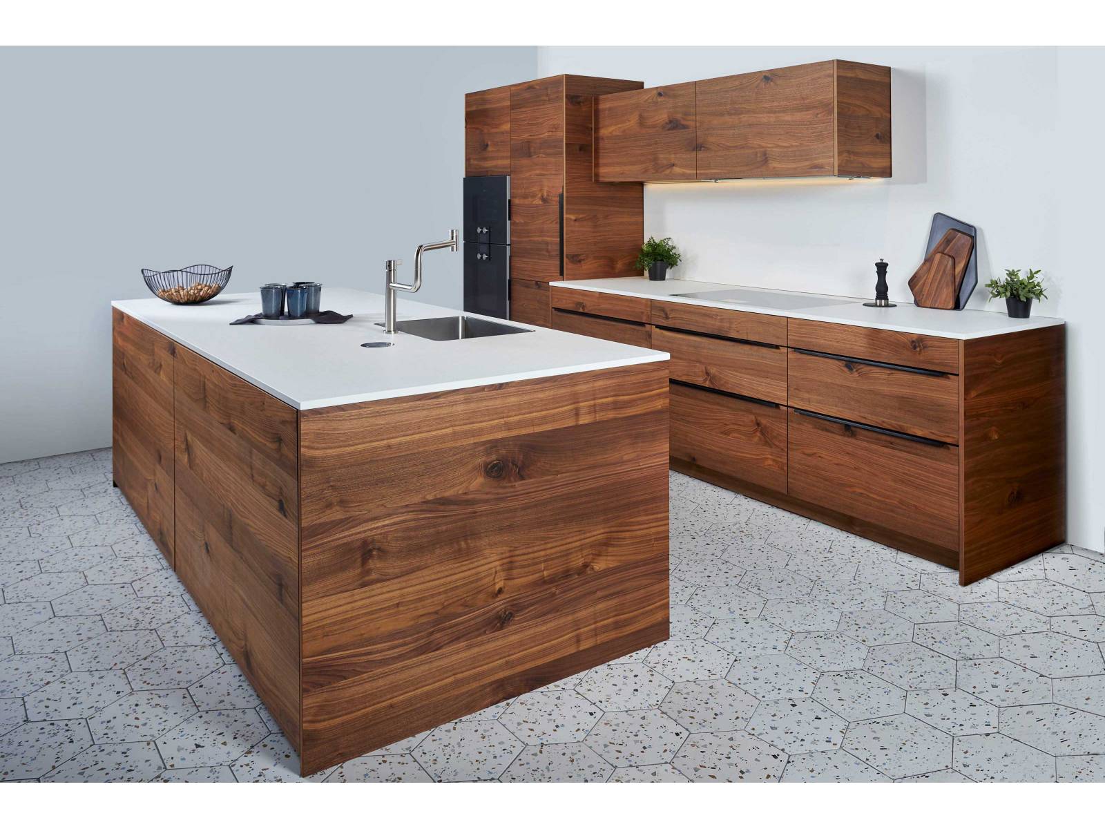 Holz in Verbindung mit der Farbe Weiss ist eine Kombination, die zeitlos und modern zugleich ist. Hier präsentiert sich die Küche in kräftigem Nussbaum mit weisser Arbeitsfläche, die durch den geschickt platzierten LED-Streifen optimal ausgeleuchtet wird. SABAG.